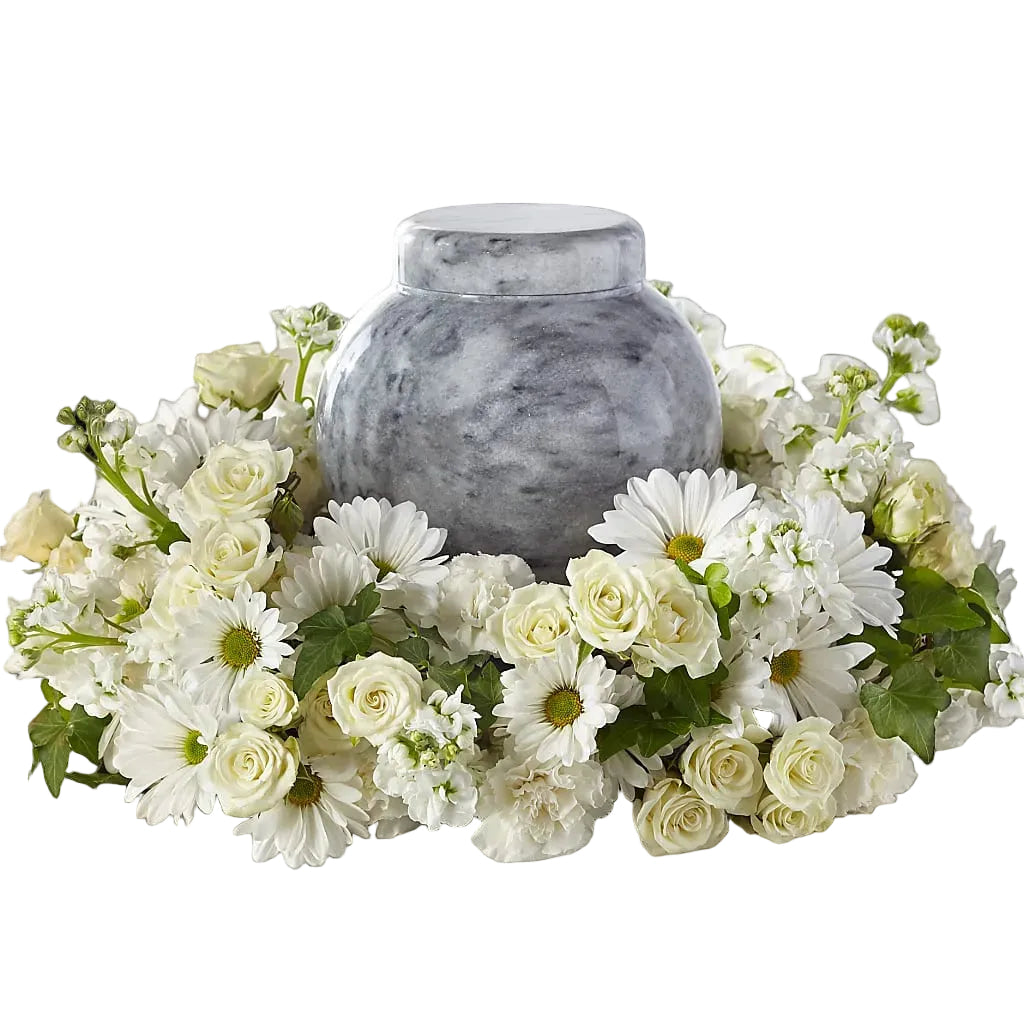 Gray marble urn surrounded by white and green flowers on a white surface.